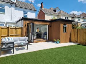 a garden room with a couch and a patio at South Coast Beach Holiday Home-3 BED-GF-Sleeps 6-Free Parking-Walk to Beach-Private Garden- Families-Professional Groups-Contractors WELCOME in Bournemouth
