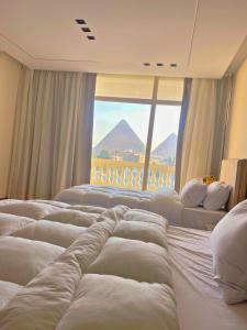 una fila de camas en una habitación con ventana en Roone pyramids view hotel, en El Cairo