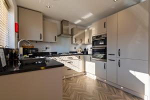 kuchnia z białymi szafkami i czarnymi blatami w obiekcie Pet friendly house by KBS StayHub Short Lets & Serviced Accommodation Innsworth with parking w mieście Down Hatherley
