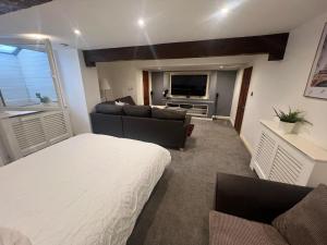 a living room with a bed couch and a tv at The basement in Bury