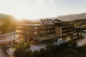 un edificio con la puesta de sol detrás de una montaña en Hotel B&B Feldmessner, en Brunico