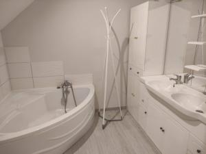 a white bathroom with a tub and a sink at Maison Proche Gare in Neufchâteau +3 photos