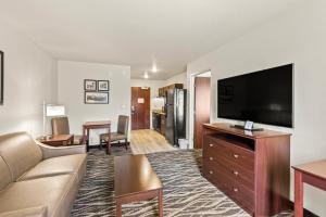 a living room with a couch and a flat screen tv at Cobblestone Hotel & Suites Waukesha West Milwaukee in Waukesha