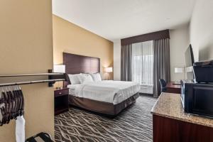 a hotel room with a bed and a flat screen tv at Cobblestone Hotel & Suites Waukesha West Milwaukee in Waukesha +49 photos