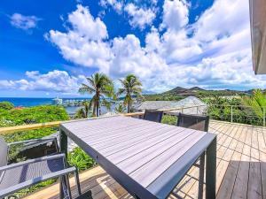 a table on a deck with the ocean in the background at Villa Olive Sea View Cocoon in Oyster Pond in Oyster Pond