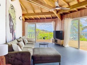 a living room with a couch and a flat screen tv at Villa Olive Sea View Cocoon in Oyster Pond in Oyster Pond +8 photos