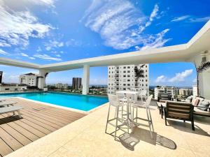Un balcón con mesa y sillas y una piscina. en Comfy 1BR Apt, King Bed, Pool, en Ensanche Quisqueya