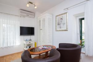 sala de estar con 2 sillas, mesa y TV en Apartments Sunce, en Split