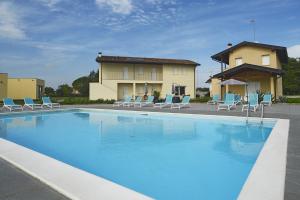 a large swimming pool with blue chairs and a house at Alloggio Agrituristico Bianchin via Trieste 67 Fiumicello-Villa Vicentina in San António
