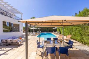 eine Terrasse mit einem Tisch und einem Sonnenschirm neben einem Pool in der Unterkunft Villa Artemisia in Peyia