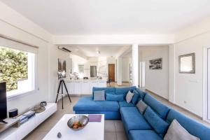 ein Wohnzimmer mit einer blauen Couch und einer Küche in der Unterkunft Villa Artemisia in Peyia