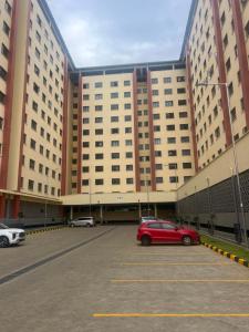 een rode auto geparkeerd op een parkeerplaats voor een groot gebouw bij The R&M Escapes in Kisumu