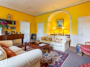 a living room with yellow walls and a piano at Kilmichael House in Brodick