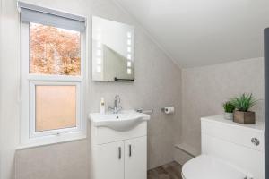 a bathroom with a sink and a toilet and a window at Woodside B & B in Keswick +4 photos