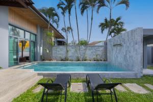 a swimming pool with two chairs and a house at Onyx Villas by TropicLook in Nai Harn Beach