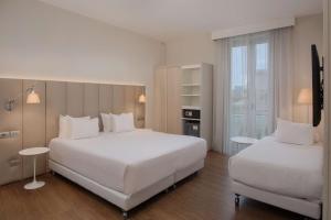 a hotel room with two beds and a window at NH Genova Centro in Genova