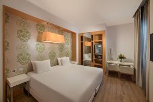 a bedroom with a large white bed and a bathroom at NH Genova Centro in Genova +42 photos