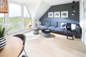 a living room with a blue couch and a table at Deichloft - mit Watt- und Hafenblick in Juist