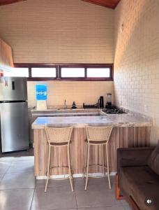 kuchnia z blatem z dwoma stołkami i lodówką w obiekcie Chalé Lounge Beach ,Praia do Maceió Camocim Ce w mieście Camocim