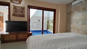 a bedroom with a bed and a tv and a window at Villa Telge in Sanur