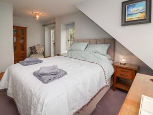 a bedroom with a white bed and a staircase at Rookery Cottage in Lynton