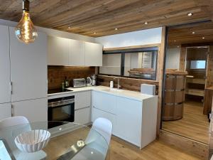 a kitchen with white cabinets and a glass table at Appartement standing -spa wellness sur les pistes in Tignes +12 photos