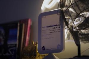 Un teléfono celular sobre un soporte junto a libros. en Nairah Residence, en Riad