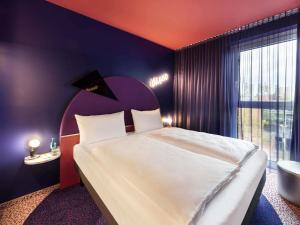 a bedroom with a large bed and a large window at ibis Styles Muenchen Perlach in Munich