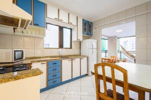 a kitchen with blue and white cabinets and a table at Apto c/ varanda e churrasq. a 290m do mar CAU0199 in Meia Praia