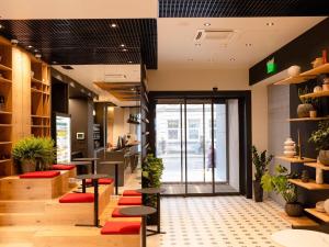 Un vestíbulo de una tienda con taburetes y plantas. en ibis Lviv Center, en Leópolis