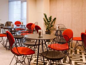 a room with tables and chairs with orange chairs at ibis Lviv Center in Lviv
