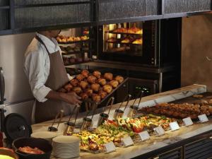 大阪市にある東急ステイ メルキュール 大阪なんばのレストランの厨房で料理を準備するシェフ