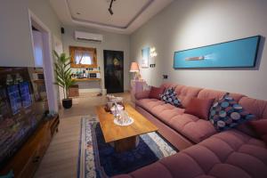 Una sala de estar con un sofá rosa y una mesa. en Nairah Residence, en Riad