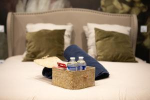 un letto con un cappello e due bottiglie d'acqua di Deluxe Studio, Dark Floral, jacuzzi, Parking Gratuit, MULHOUSE CENTRE a Mulhouse