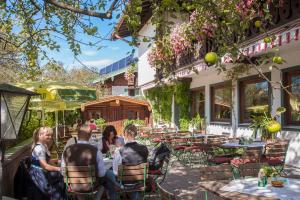 people sitting at tables outside of a restaurant at Gasthof-Appartements Vroni - Chiemgau Karte in Inzell