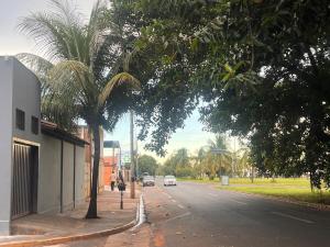 a street with palm trees and a car on the road at House Amorim 13 min Parque peão in Barretos