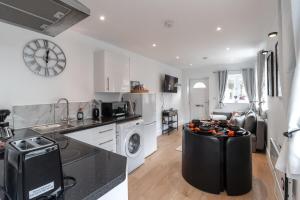 a kitchen with a stove top oven next to a living room at Luxury 1 Bed Apartment Bromley in Bickley