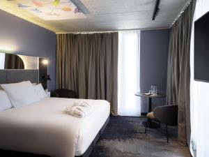 a hotel room with a white bed and a table at Mercure Hotel Delémont in Delémont