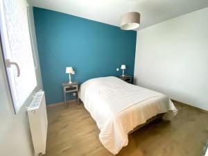 a bedroom with a white bed and blue walls at Ty Cath - Maison en bord de mer in Guissény