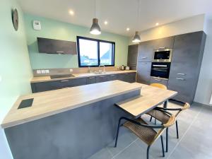 a kitchen with a counter and a table and chairs at Ty Cath - Maison en bord de mer in Guissény