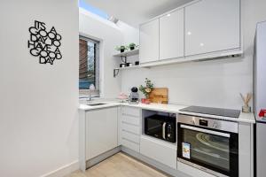 a white kitchen with white cabinets and a dishwasher at Edegely House in Stockport +7 photos