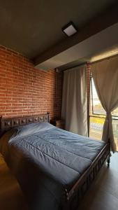a bed in a room with a brick wall at TempoJUY in San Salvador de Jujuy