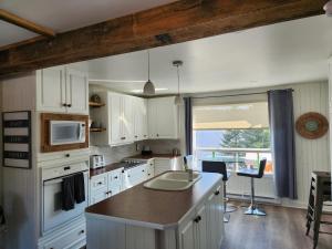 a kitchen with white cabinets and a large window at Chalet Lac Édouard cozy in La Tuque