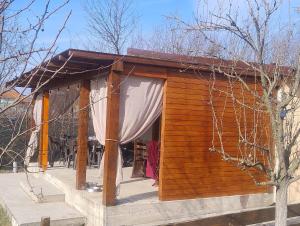 eine kleine Holzhütte mit einem weißen Vorhang in der Unterkunft Casuta din Livada 2 