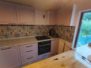 eine Küche mit weißen Schränken und einem Herd mit Backofen in der Unterkunft Casuta din Livada 2 