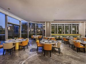 a restaurant with tables and chairs and large windows at Novotel Shanghai Caohejing in Shanghai