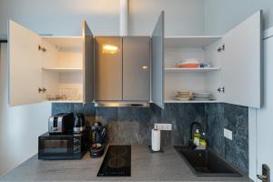 a kitchen with white cabinets and a microwave at Elegant city center apartment with free parking by Polo Aparments in Kaunas +21 photos