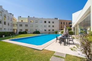方The Sun and Sea Apartment by Minho's Guest的建筑物旁边有一张桌子和椅子的游泳池