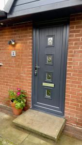 eine blaue Tür an einem Backsteinhaus mit einer Topfpflanze in der Unterkunft Modern, Spacious Home Near Manchester - Perfect for Families group in Hollinwood