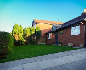 ein Haus mit einem Rasen davor in der Unterkunft Modern, Spacious Home Near Manchester - Perfect for Families group in Hollinwood